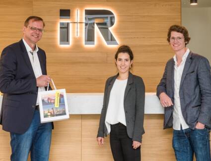 Michael Kofler aus Allensbach (links) ging als Gewinner aus dem Ideenwettbewerb für die Quartiersbezeichnung hervor. Im neuen i+R Büro in Konstanz konnte er von Maria Wechsel und Marius Reck (beide i+R) den Gutschein für die Bregenzer Festspiele entgegenn © ©Chris Danneffel